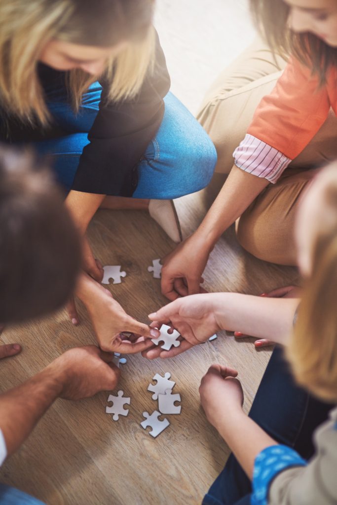 Group of hands working on a jigsaw puzzle.